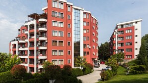 Un edificio residencial de varios pisos con balcones, unidades de aire acondicionado y un ascensor central de vidrio.
