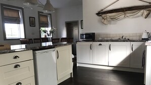 A kitchen with white cabinets, a dishwasher, a microwave, and a sink. - The Old Boathouse (Enniskillen)