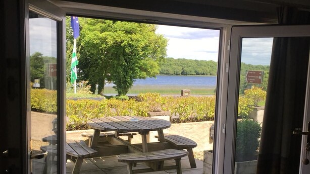 A sliding glass door leading to an outdoor patio with a picnic table and a view of a lake. - The Old Boathouse (Enniskillen)