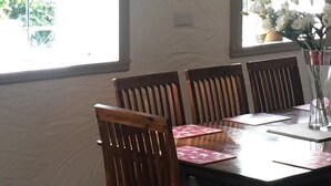 A dining area with a table set for four, surrounded by wooden chairs. There are two pendant lights hanging above the table. - The Old Boathouse (Enniskillen)
