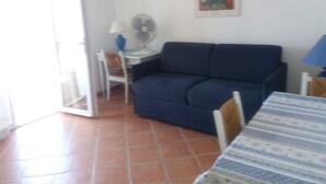 A living room with a blue sofa, a small table with a lamp, a chair, and a painting on the wall. - Exceptional sea view apartment in detached villa Côte d'Azur (Rayol-Canadel-Sur-Mer)