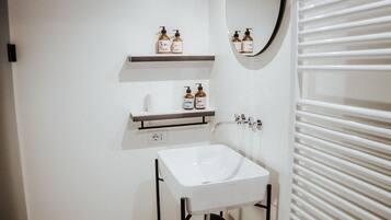 Un baño moderno con lavamanos, espejo y toallero blancos.