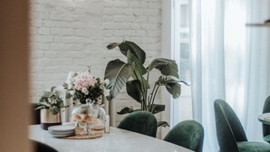 A dining area with a white brick wall, green chairs, a white table, and a neon sign. - Cà Bèla - Porta Romana (Milan)