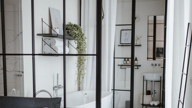 A modern bedroom with a bed, a small table, and a view into a bathroom with a bathtub and shower. - Cà Bèla - Porta Romana (Milan)