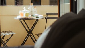 A balcony with a table set for breakfast, including a bottle, a glass, and a plate with food. - Cà Bèla - Porta Romana (Milan)