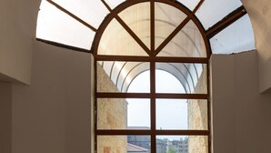 A corridor with a large arched window, a staircase, and a view of buildings outside. - Apartment in Vista Del Mar (Ravda)