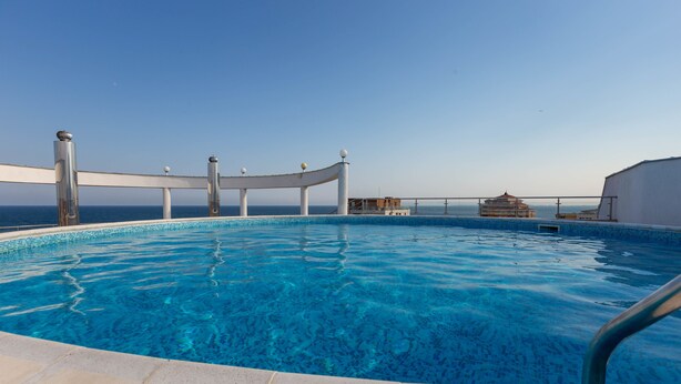 A clear blue pool with a white deck and metal railings, overlooking the sea. - Apartment in Vista Del Mar (Ravda)