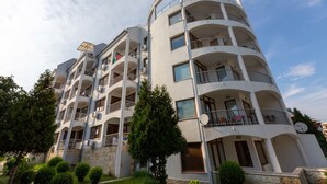 A multi-story residential building with balconies, satellite dishes, and a stone facade. - Apartment in Vista Del Mar (Ravda)