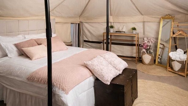 A tented room with a bed, a desk, a mirror, and a hanging light fixture. - Desert Wonders Camp (Bidiya)