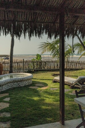 Un espacio exterior techado con piscina, sillas de descanso y vistas a la playa.