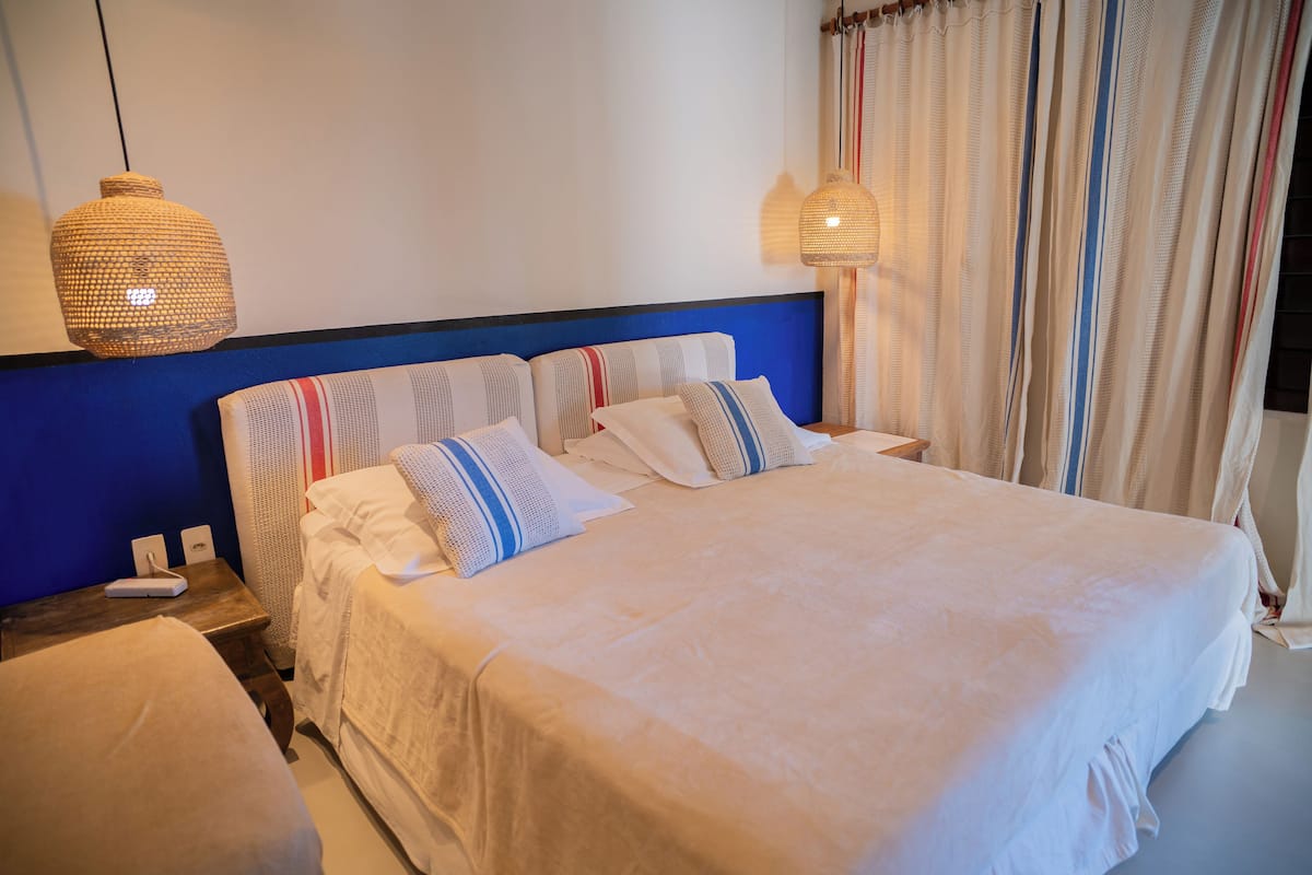 Ein Hotelzimmer mit einem großen Bett, einem Nachttisch mit Telefon und einer Hängelampe.