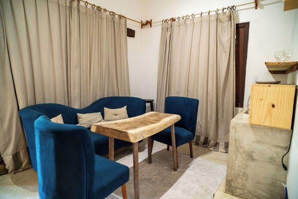 A living room with a blue sofa, a wooden coffee table, and beige curtains. - Zebra Boutique Hotel (Beberibe)