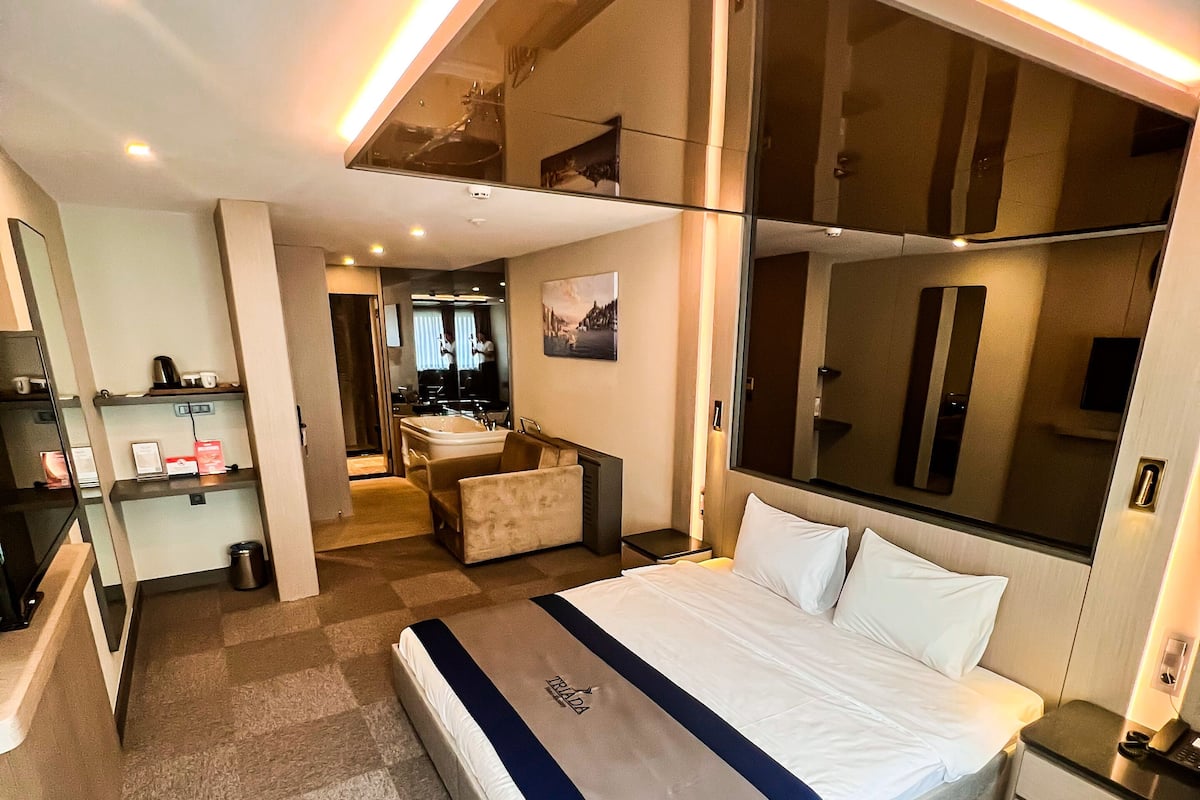 A modern hotel room with a large bed, a desk, and a seating area.