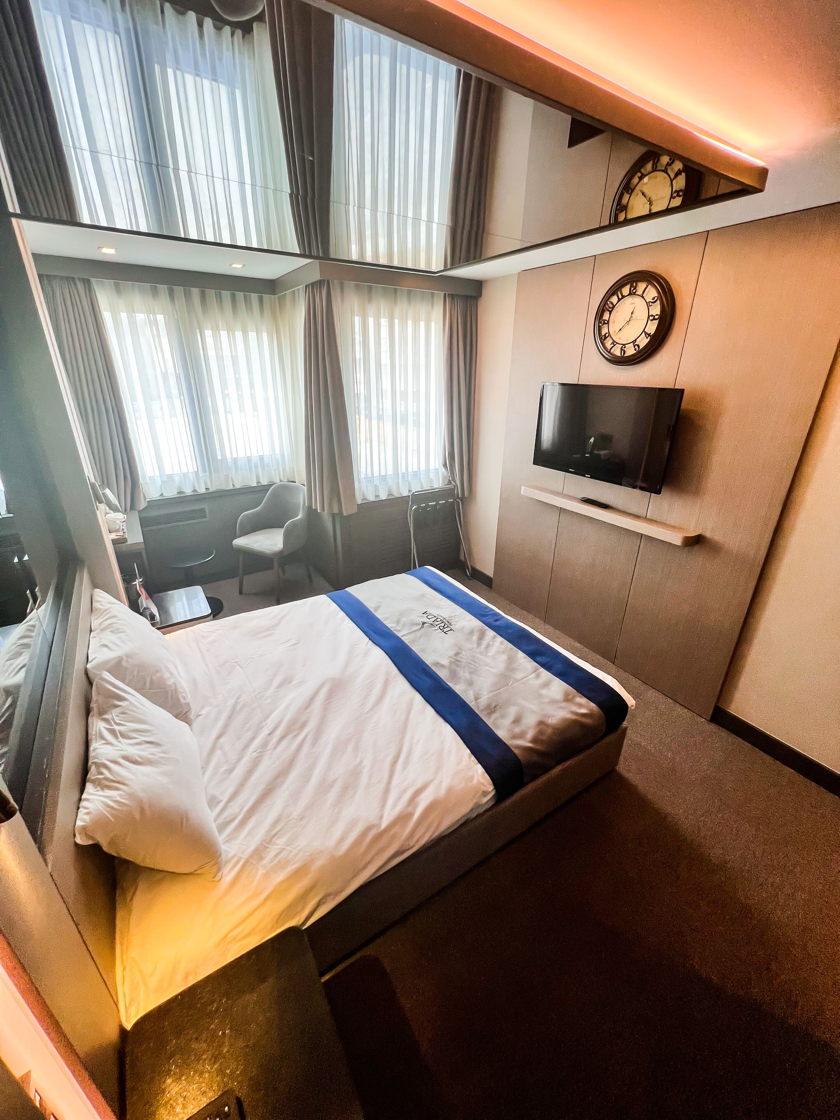 Habitación de hotel con cama, televisión montada en la pared, escritorio y silla.