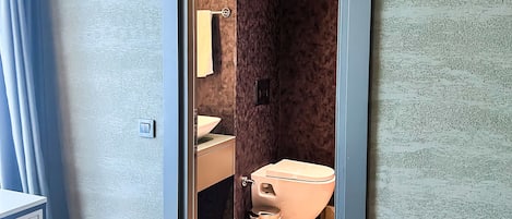 Un baño moderno con inodoro, lavamanos y espejo.