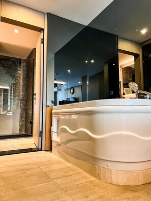 A modern bathroom with a large bathtub, a mirror, and a wooden floor. - Triada Hotel Karakoy (Istanbul)