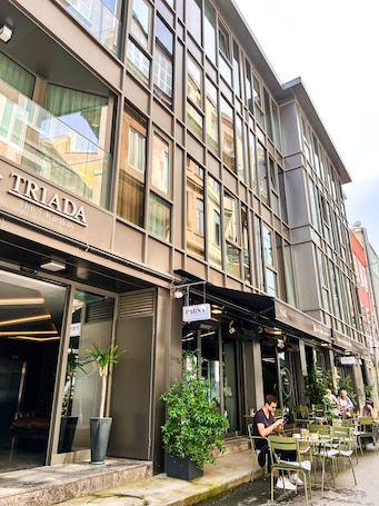 A modern hotel with a glass facade, outdoor seating area, and a visible restaurant named PARSA.