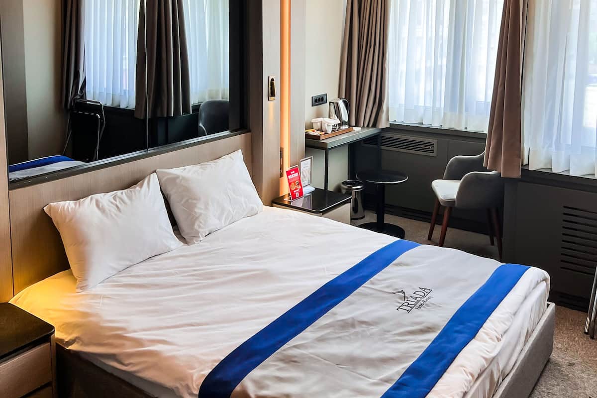 A hotel room with a large bed, a desk, and a chair.