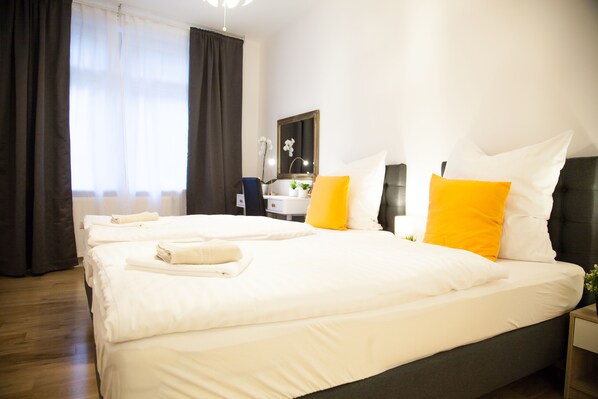 A hotel room with a large bed, a bedside table, a mirror, and a window with curtains. - Apartmenthaus Heidelberg (Heidelberg)