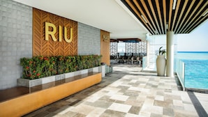 Un hall d'hôtel moderne avec une enseigne « RIJU », un espace piscine et des sièges en plein air.