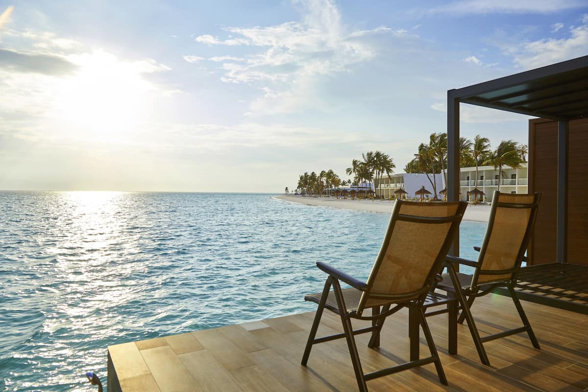 A deck with two chairs overlooking a beach and ocean.