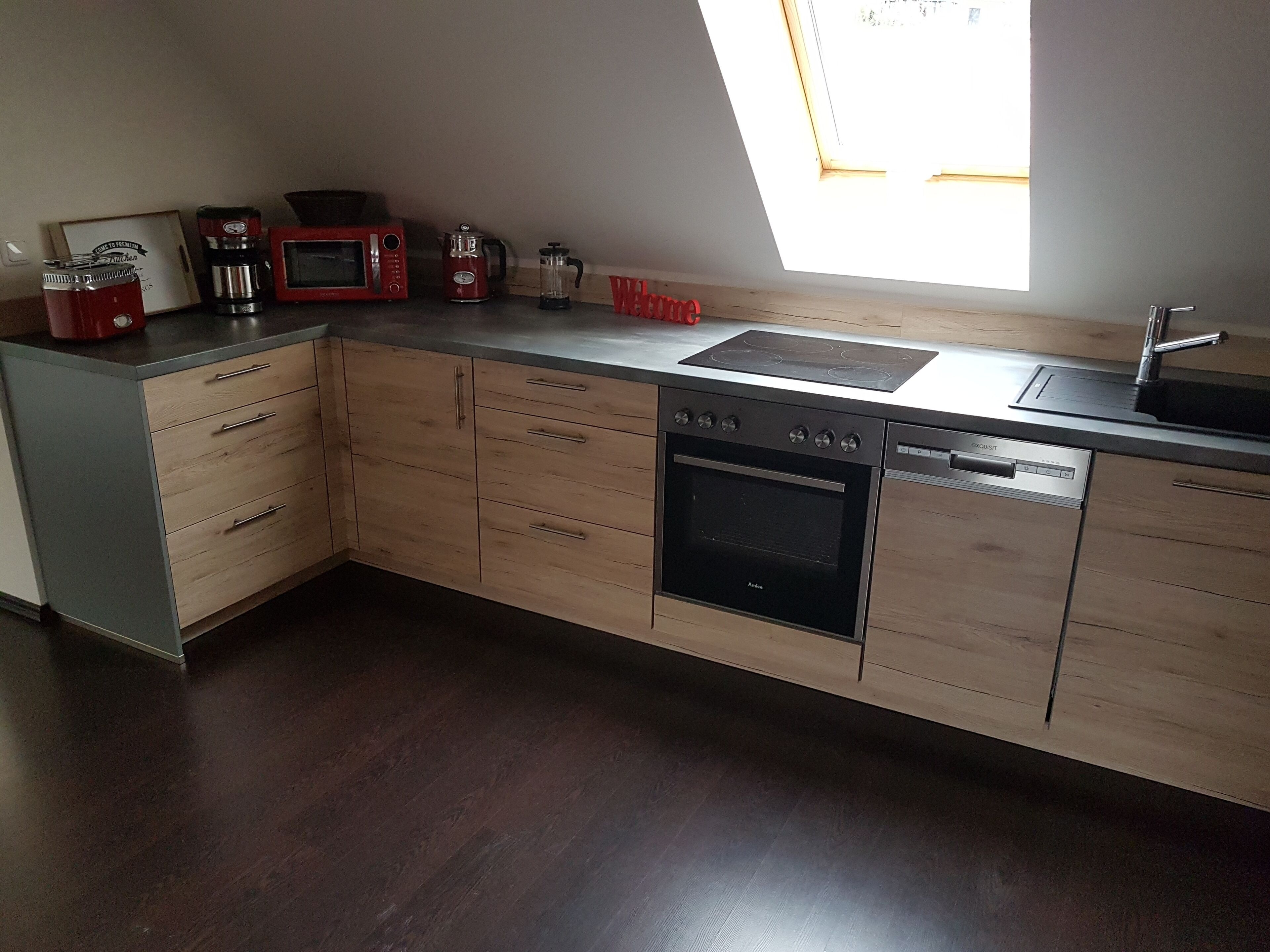 A modern kitchen with wooden cabinets, a built-in oven, a microwave, a coffee maker, and a sink.