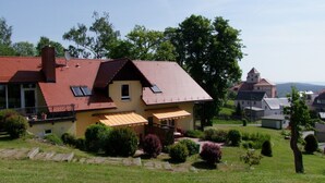 A two-story house with a red roof, a yellow facade, and a small balcony. - Ferienwohnung Schloss Schönberg (Bad Brambach)