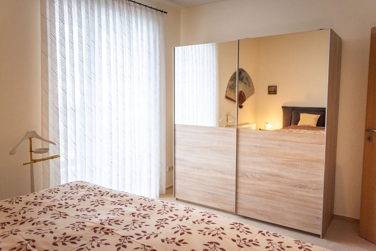 Un dormitorio con cama, armario y espejo.