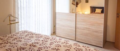 Une chambre à coucher avec un lit, une armoire et un miroir.