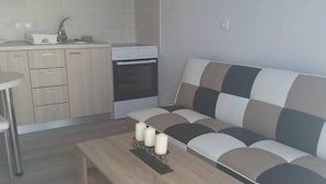 A modern kitchen with a built-in oven and a dining area with a wooden table and a sofa. - Nianthy Apartments (Rhodes)