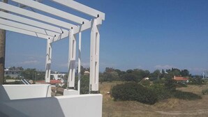 A white pergola structure with a clear view of a rural landscape, including houses and greenery. - Nianthy Apartments (Rhodes)