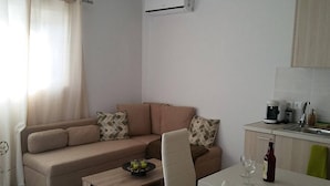 A living room with a sofa, a coffee table, and a dining table with a wine glass and bottle. - Nianthy Apartments (Rhodes)