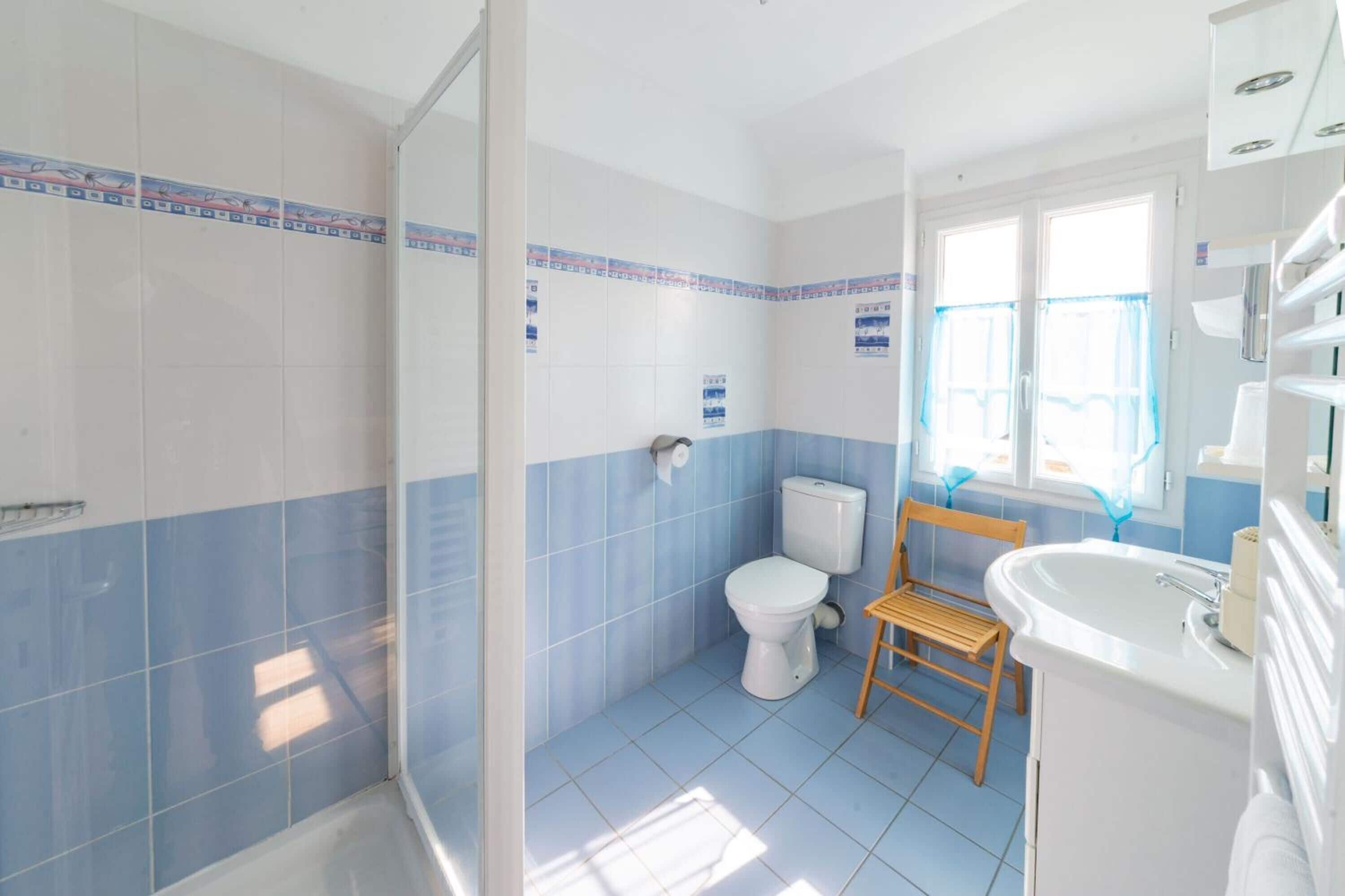 A bathroom with a toilet, shower, and sink.