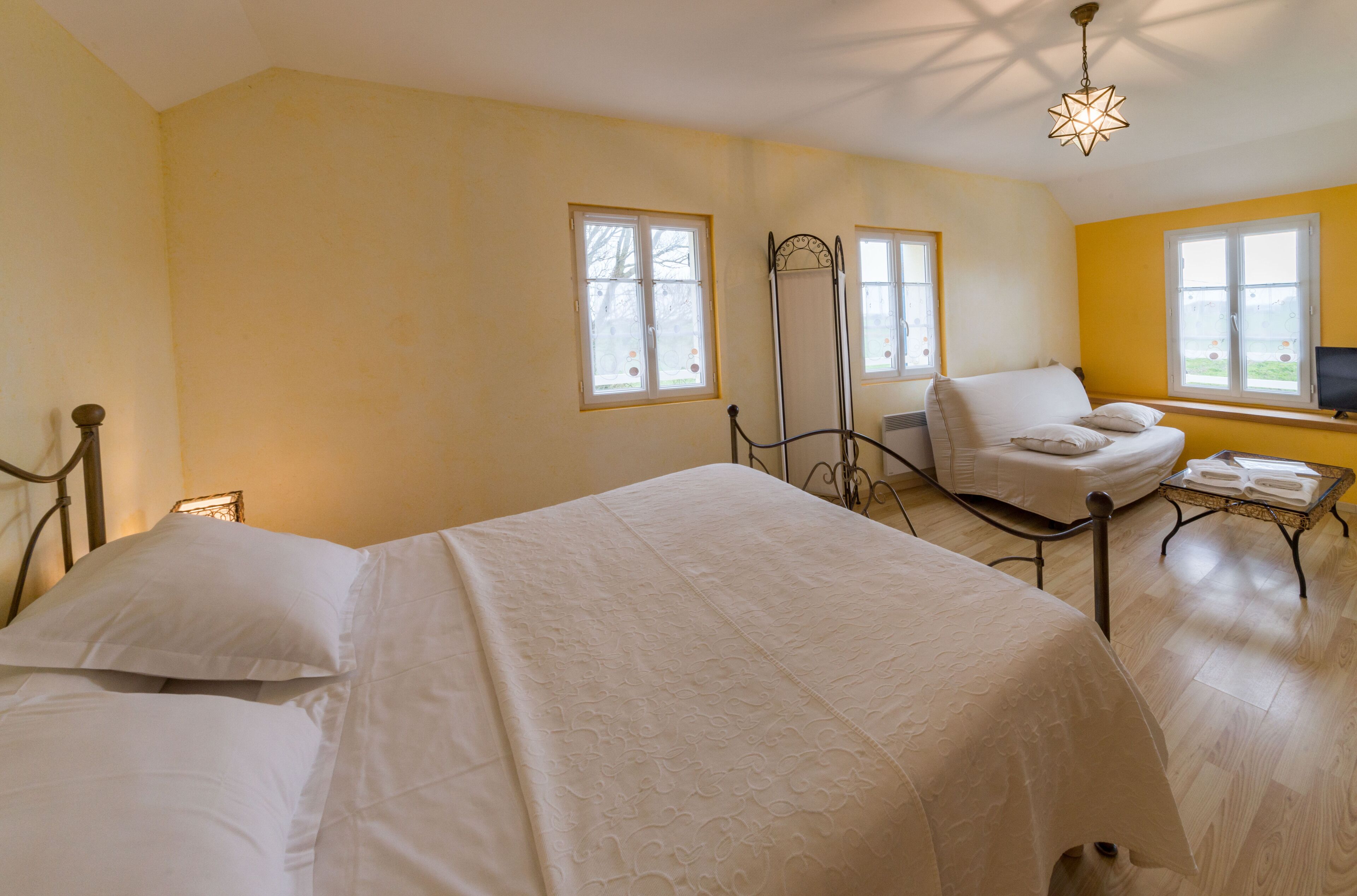 A bedroom with two beds, a chair, a table with towels, and a TV.