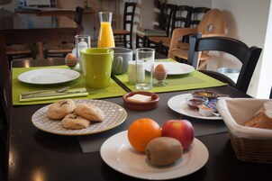 Uma mesa de café da manhã com pratos de comida, um copo de suco de laranja e uma cesta de pão.