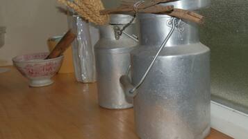 A kitchen with stainless steel appliances, a wooden spoon in a bowl, and a rustic decoration with wheat stalks and cinnamon sticks.