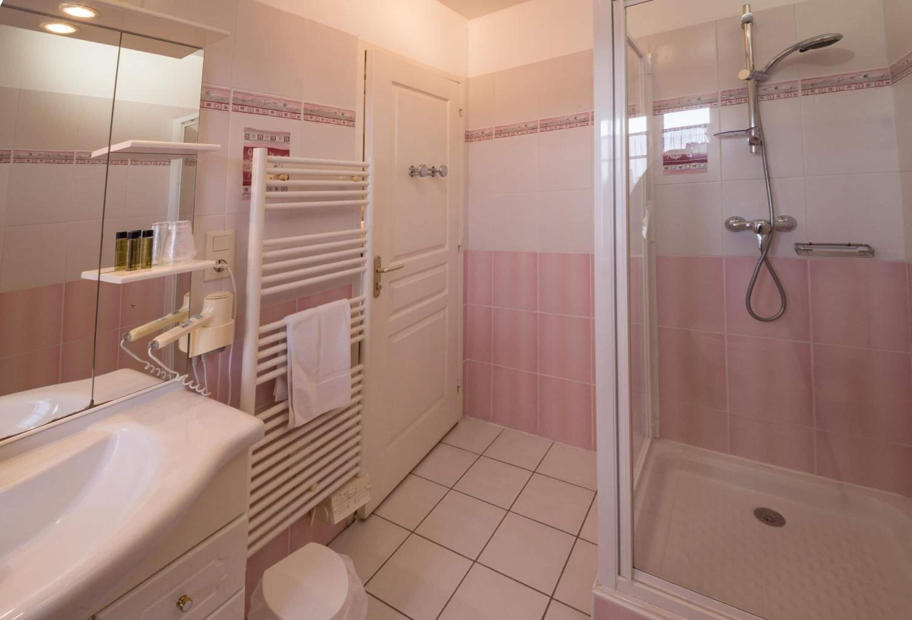 Een badkamer met een wit wastafel, toilet, douche met glazen deur en een handdoekhouder.