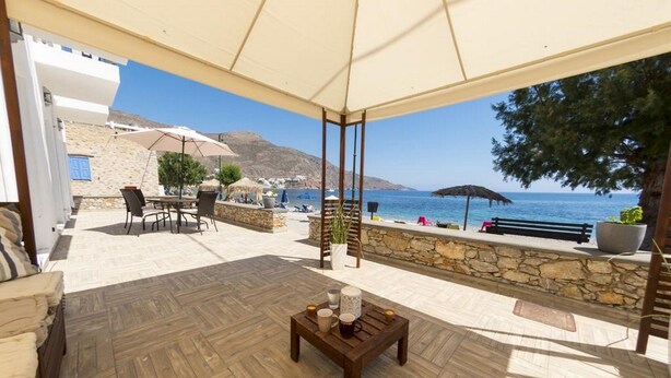 Une terrasse avec un plancher en bois, une table décorée de bougies et une vue sur la mer et les montagnes.