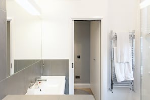 A modern bathroom with a white sink, a mirror, and a towel rack. - Chelsea Italian Design Home with Terrace (London)