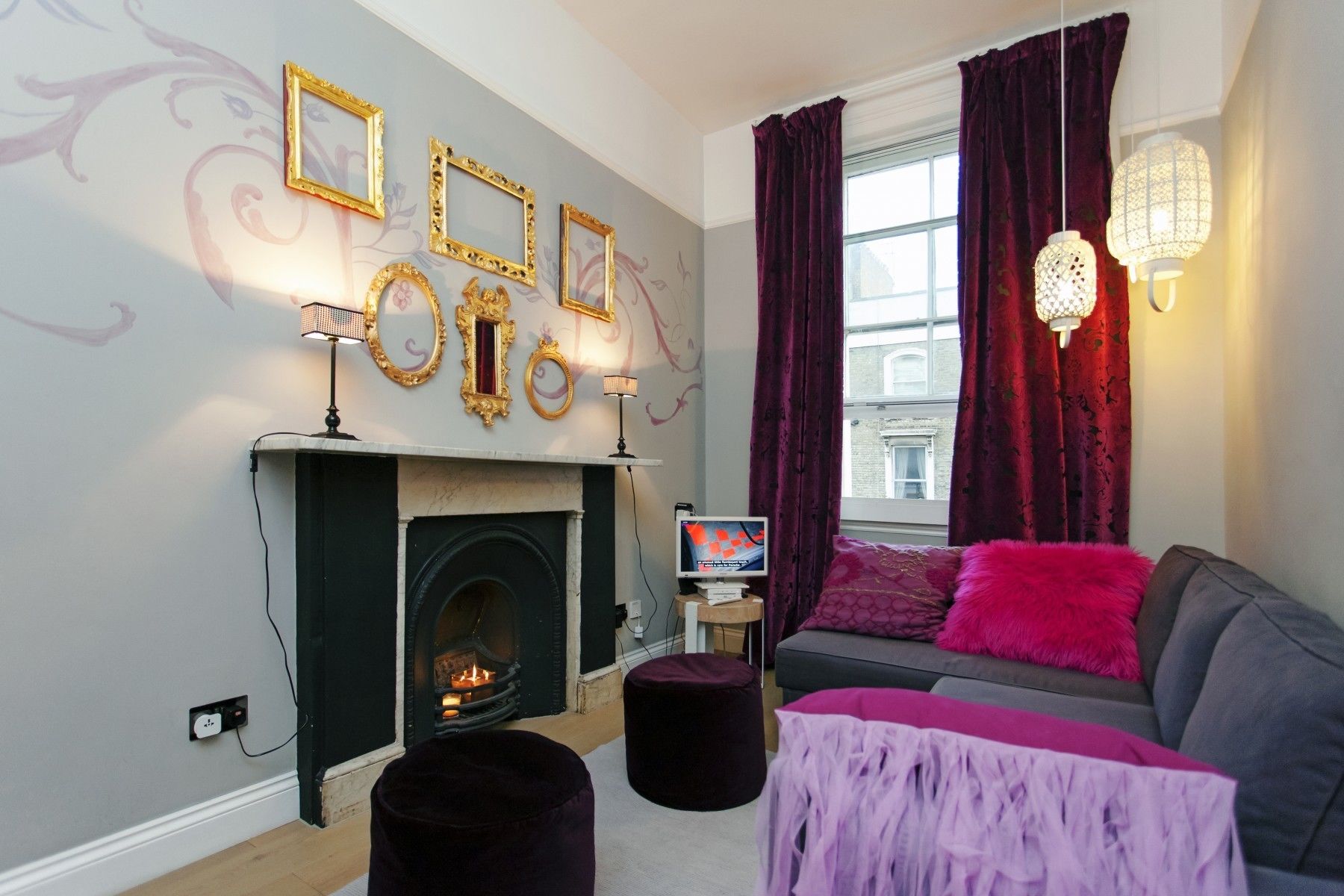 Un salon chaleureux avec une cheminée, un canapé, un téléviseur et des œuvres d’art décoratives accrochées au mur.
