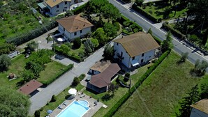 An aerial view of a residential area with houses, a swimming pool, and a well-maintained lawn.