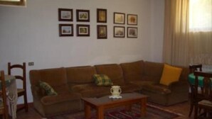 A living room with a brown sofa, a coffee table, and a rug. There are framed pictures on the wall.