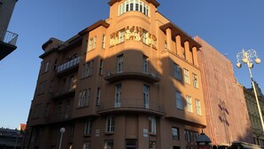 En bygning med flere etager, et buet hjørne, store vinduer og en balkon.