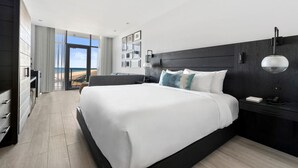A modern hotel room with a large bed, a desk, and a view of the ocean. - Wave Resort (Long Branch)