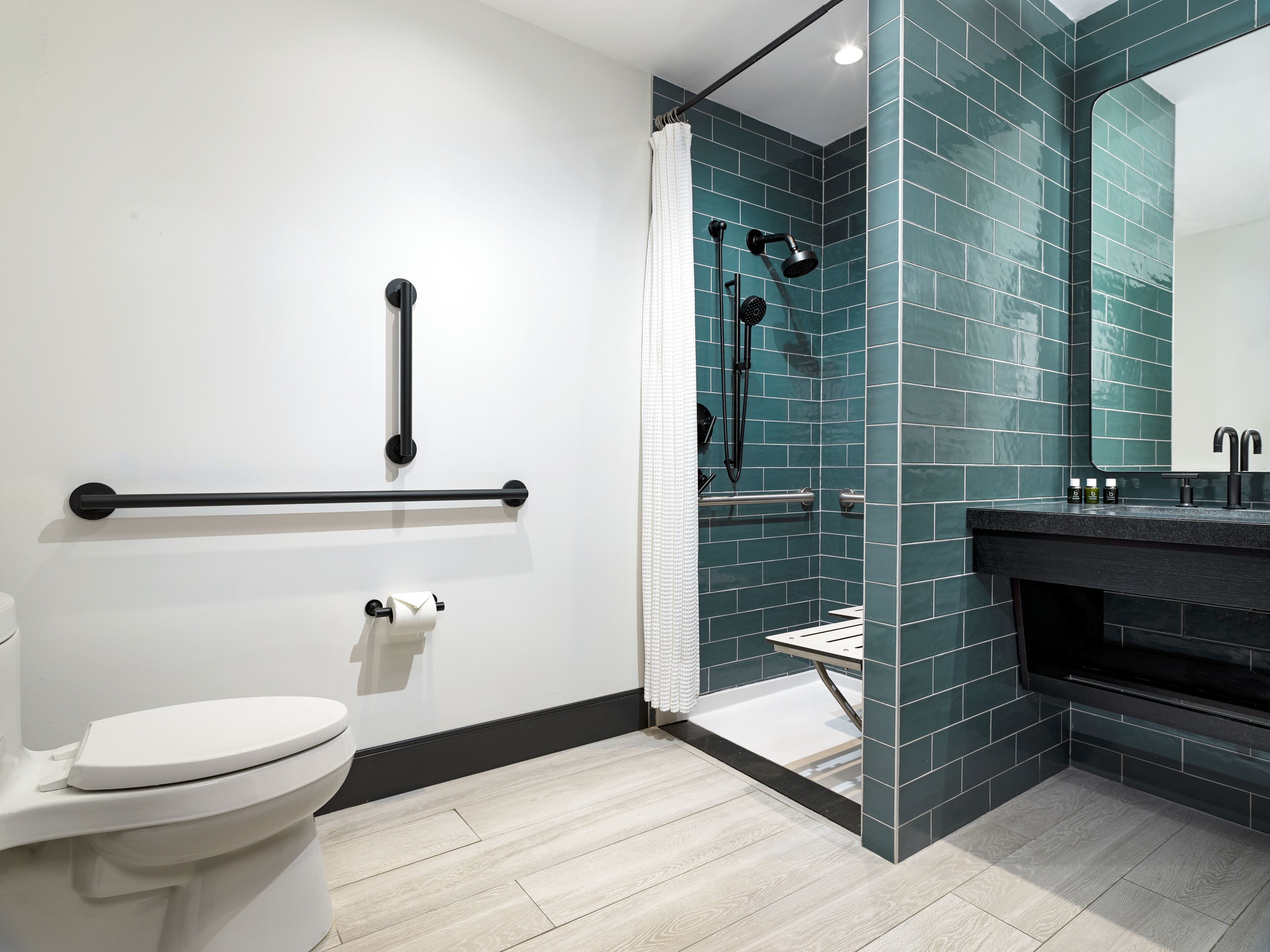 A modern bathroom with a white toilet, a shower with a glass door, and a black sink with a mirror.