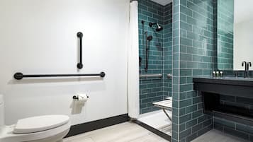A modern bathroom with a white toilet, a shower with a glass door, and a black sink with a mirror.