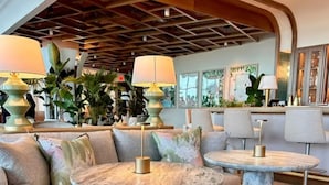 A modern lounge area with a sofa and two round tables, each with a lamp. - Wave Resort (Long Branch)