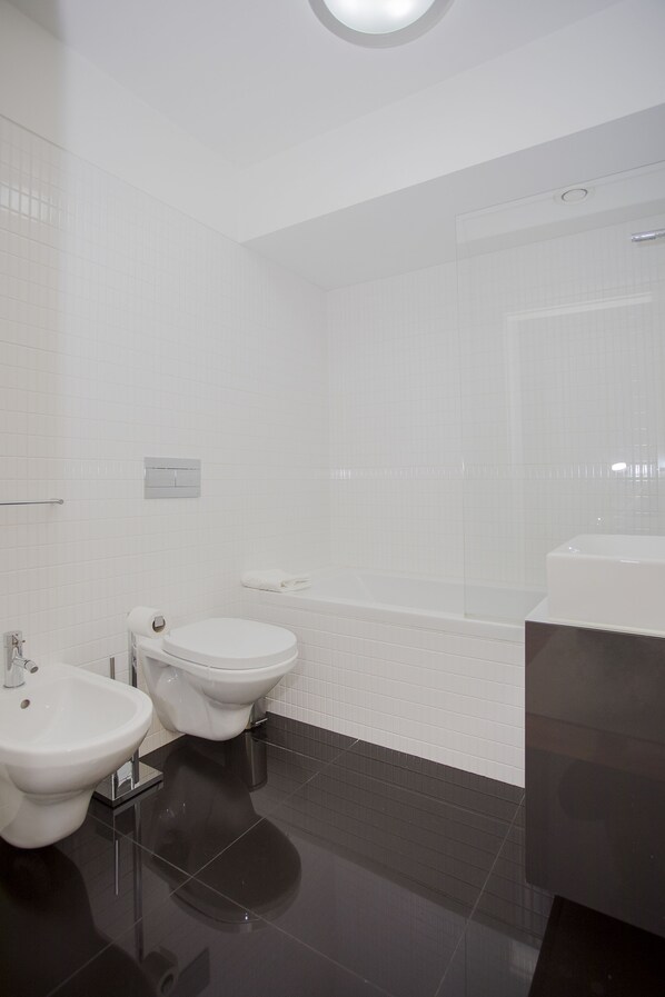 A modern bathroom with a toilet, bidet, and sink.