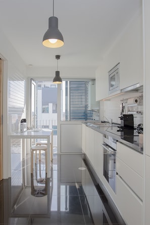 Modern kitchen with sleek cabinetry, black countertop, and a large window offering a view.