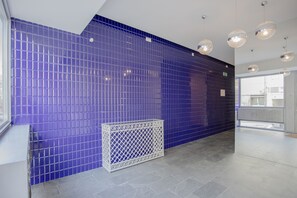 Contemporary interior with a vibrant blue-tiled wall, elegant console table, and grey tile flooring.